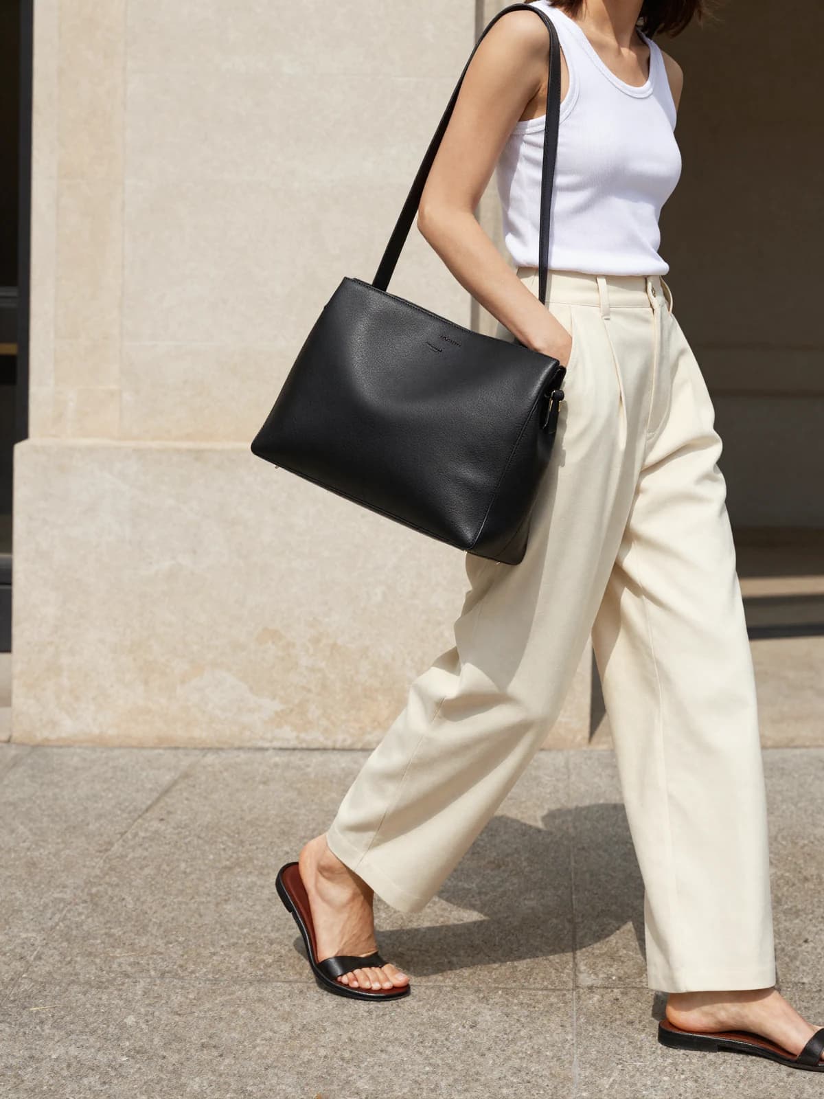 A black leather shoulder bag styled with a neutral city look